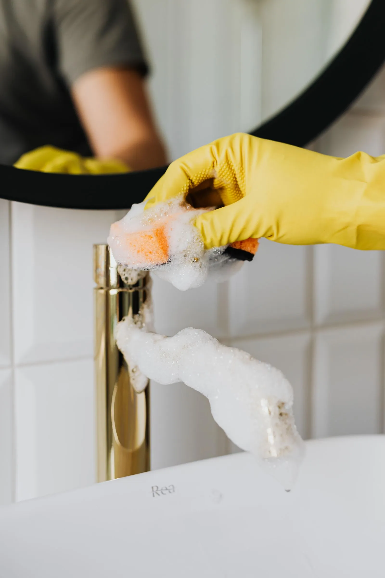 A Spray Pro Clean cleaner scrubbing a bathroom faucet until it shines
